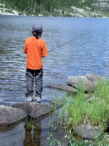 Photo of a boy fishing on the shores of a lake.